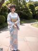 A woman in a blue kimono standing on a sidewalk.