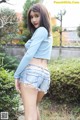 A woman in a blue shirt and denim shorts posing for a picture.