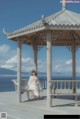 A woman sitting on a bench in front of a gazebo.